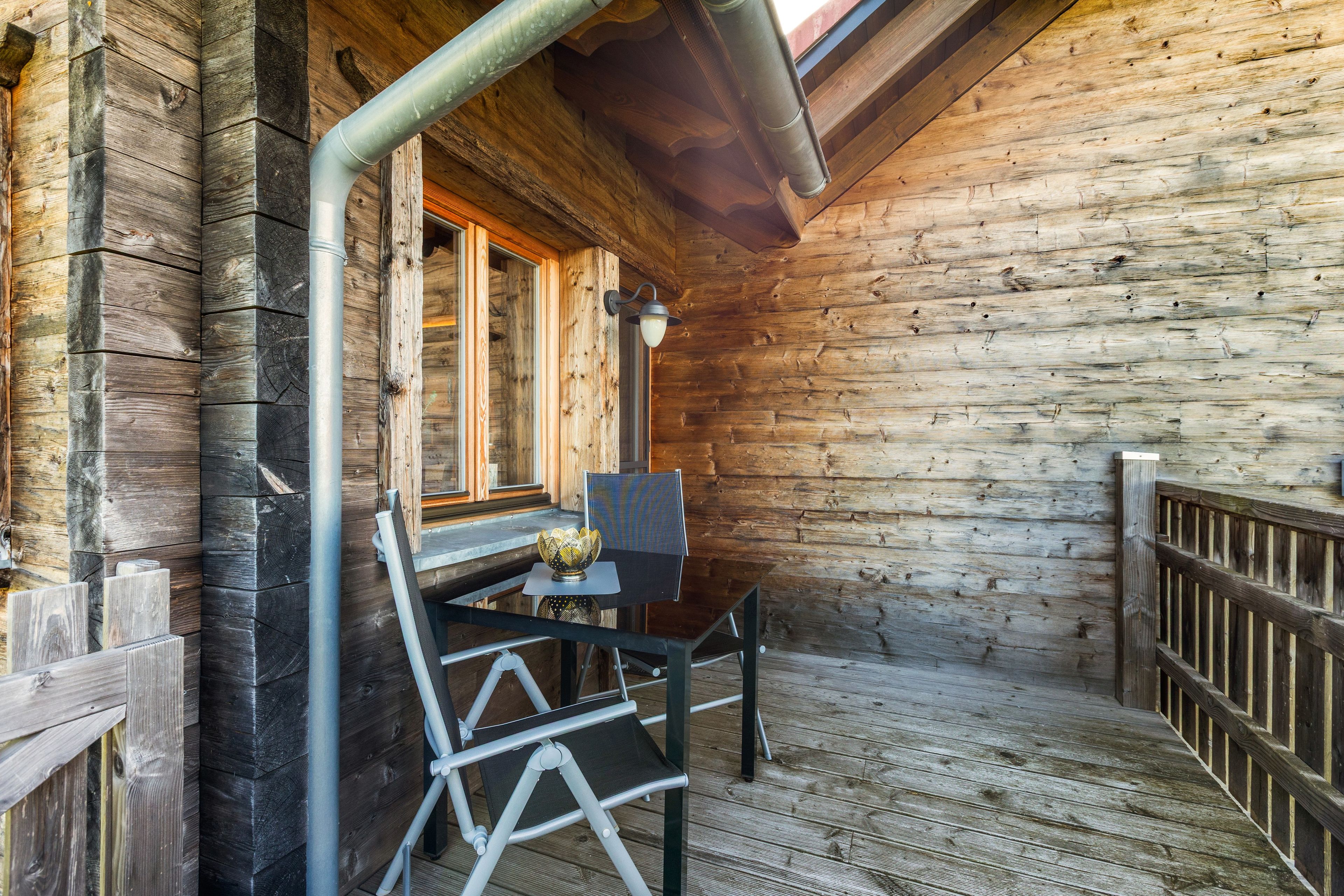 Eine Holzhütte mit einem Balkon, einem Tisch mit einer dekorativen Schale und einem Stuhl.
