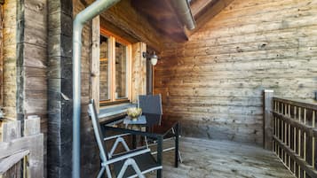 Eine Holzhütte mit einem Balkon, einem Tisch mit einer dekorativen Schale und einem Stuhl.