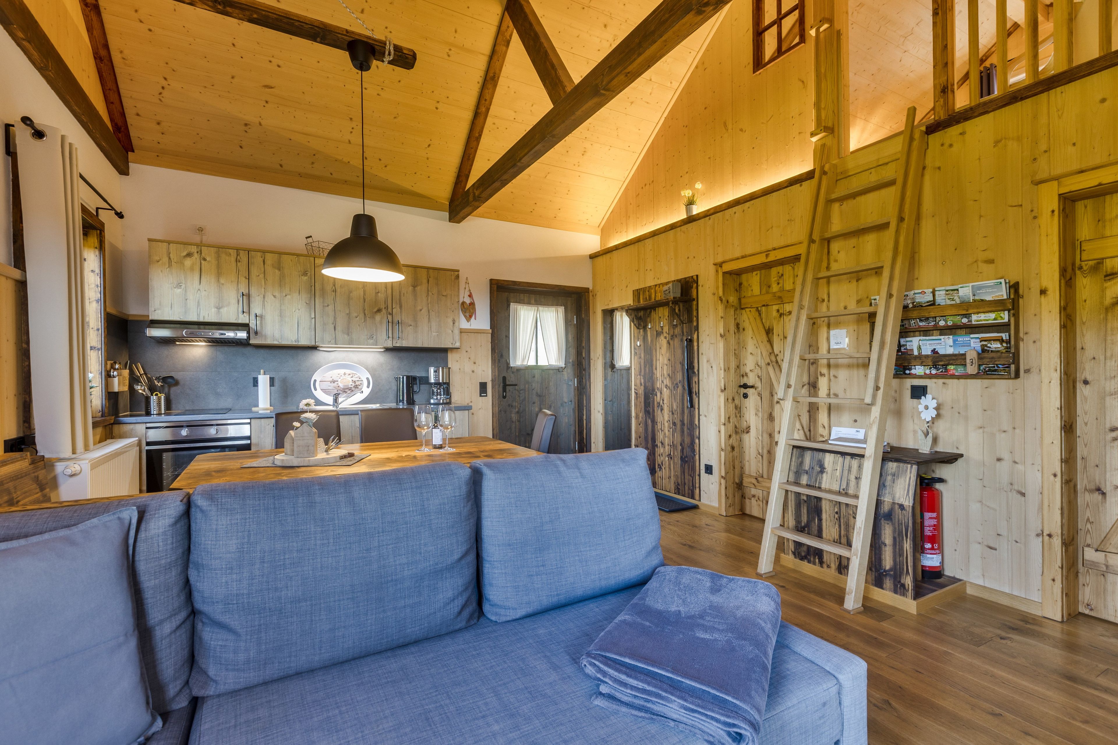 Un intérieur chaleureux avec un coin repas, des murs en bois et une chambre à coucher située en mezzanine.