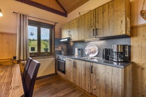 A kitchen with wooden cabinets, a built-in oven, and a coffee maker. - Chalet Oberwald 4 with Private Terrace, Garden, Sauna, Wi-Fi, and Parking (Schotten)
