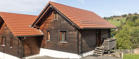 A wooden house with a sloped roof and a gravel driveway.