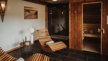 Una spa con pareti in legno, una panca di legno, un tavolino con candele e un angolo doccia.