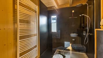 A modern bathroom with a wooden interior, a glass shower enclosure, and a small stool.