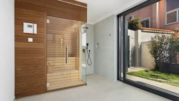 Ein modernes Badezimmer mit einer Duschkabine aus Glas, Holzvertäfelung und Blick ins Freie.