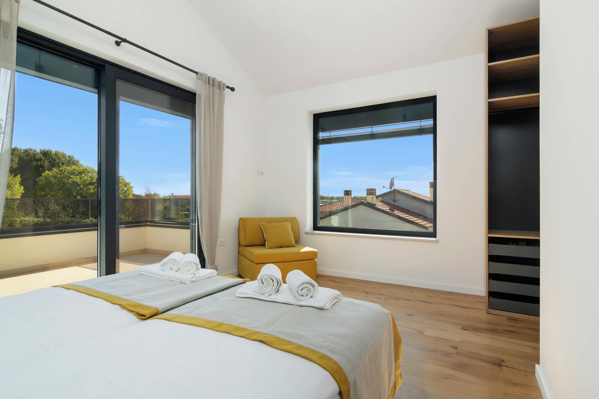 A hotel room with two beds, a sofa, a large window, and a view of buildings.