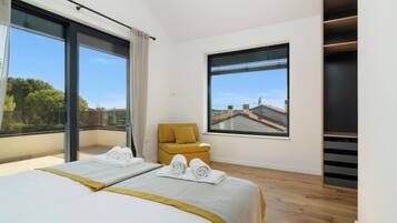A hotel room with two beds, a sofa, a large window, and a view of buildings.