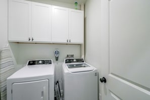 A laundry room with two washing machines, a dryer, and a cabinet above. - Little Rock Family Home, 1 Mi to Dtwn (Little Rock)