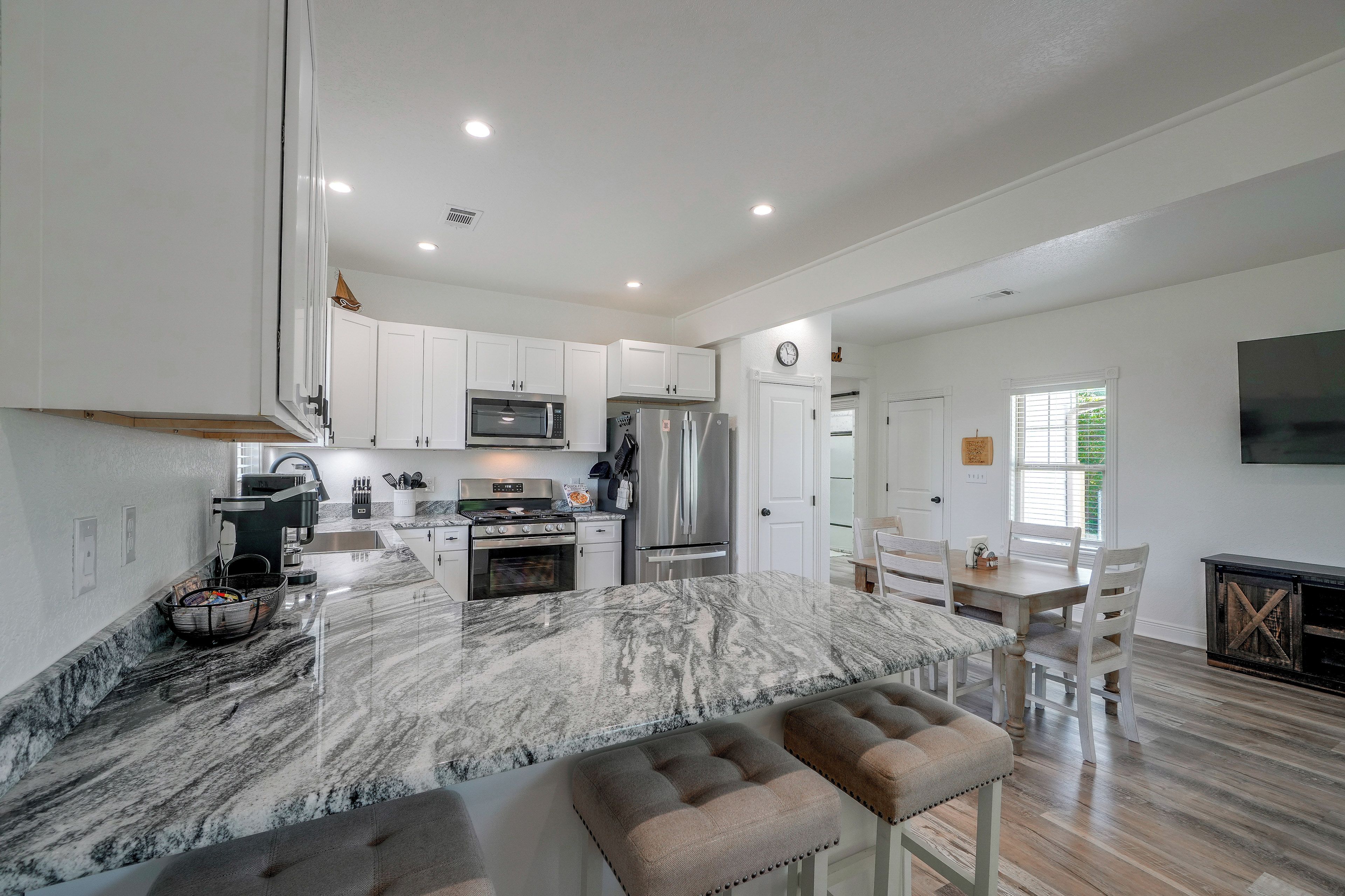 A modern kitchen with white cabinets, a marble island, and stainless steel appliances.