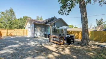 A residential property with a detached garage, a covered outdoor seating area, and a barbecue grill.