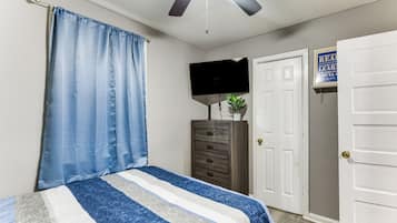 A bedroom with a bed, a dresser, a television, and a door.