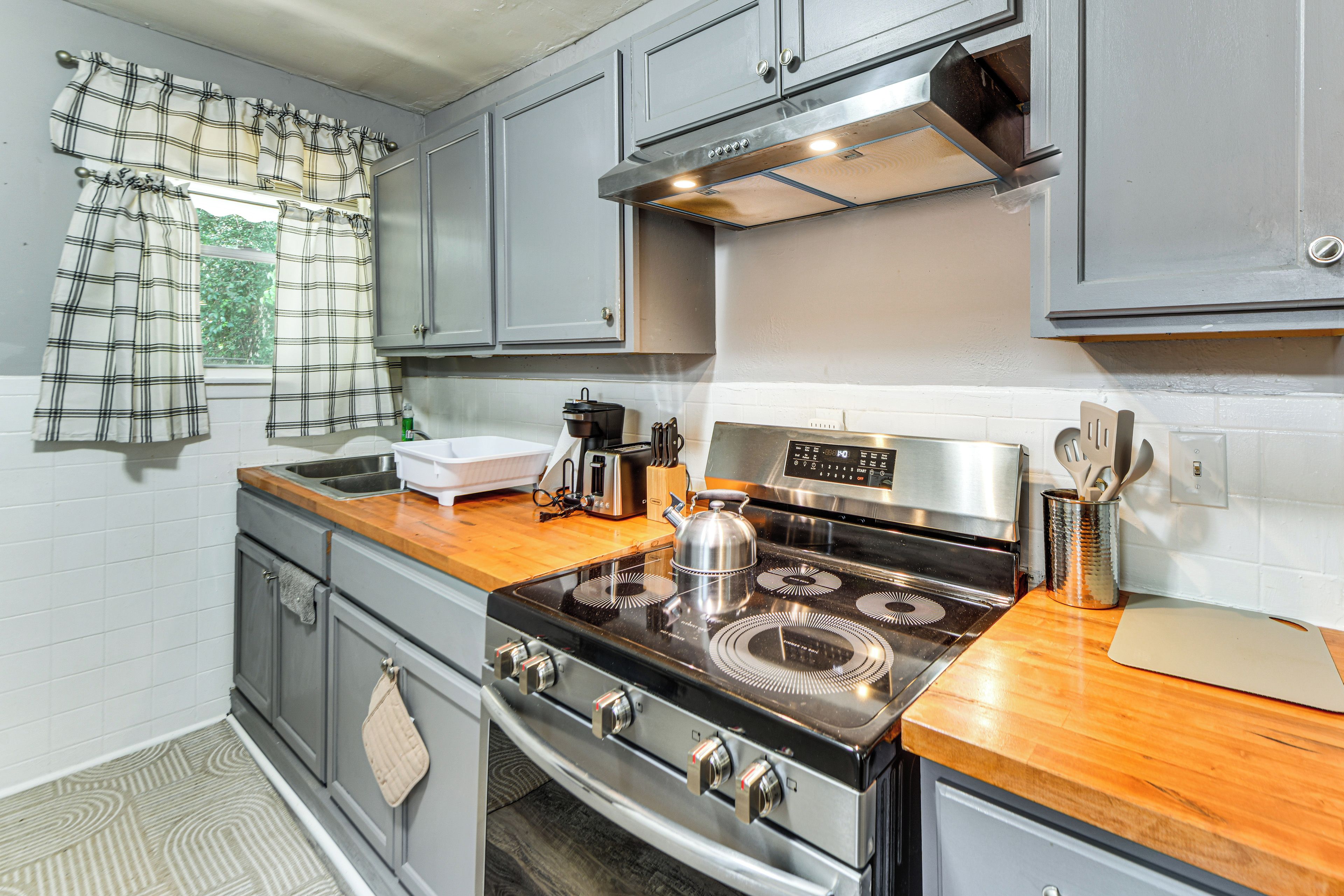 A kitchen with a stainless steel stove, a coffee maker, and a kettle on the counter.