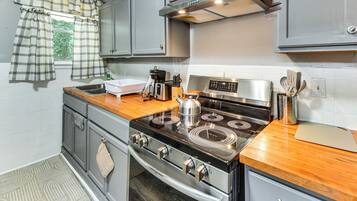 A kitchen with a stainless steel stove, a coffee maker, and a kettle on the counter.