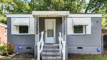 A two-story house with a front porch, a door, and two windows.