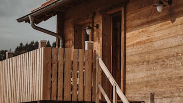 Une cabane en bois dotée d’une terrasse en bois et d’un escalier menant à une porte.