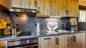 A modern kitchen with wooden cabinets, a built-in oven, a coffee maker, and a sink.