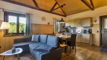 A cozy living room with a sofa, a dining table, and a kitchen area with wooden cabinets.