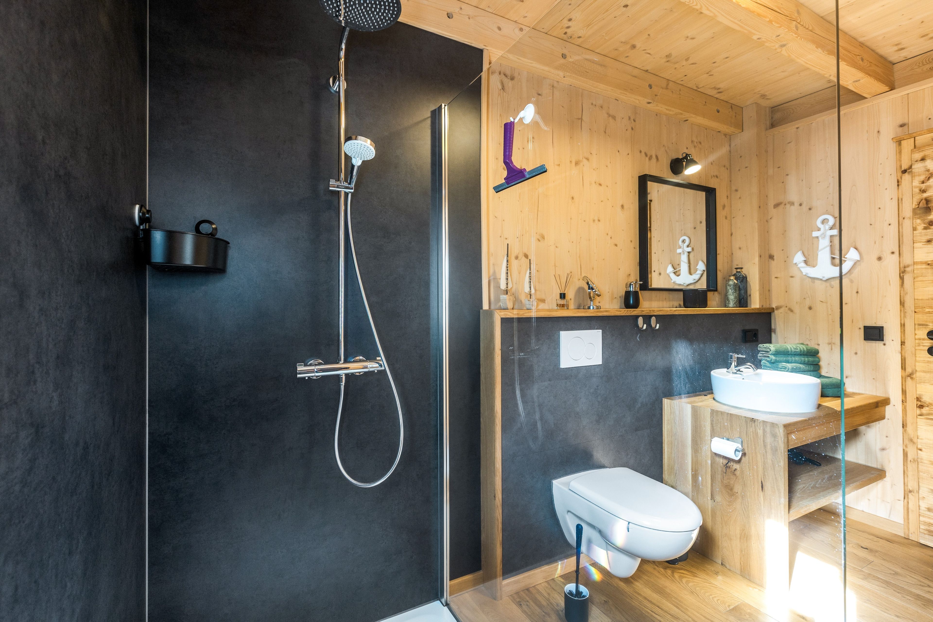 A modern bathroom with a glass shower enclosure, a wooden vanity with a sink, and a toilet.