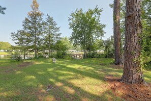 A grassy outdoor area with trees, a stone bench, and a small stone structure. - Lake Marion Retreat Dock Days & Backyard Nights (Summerton)