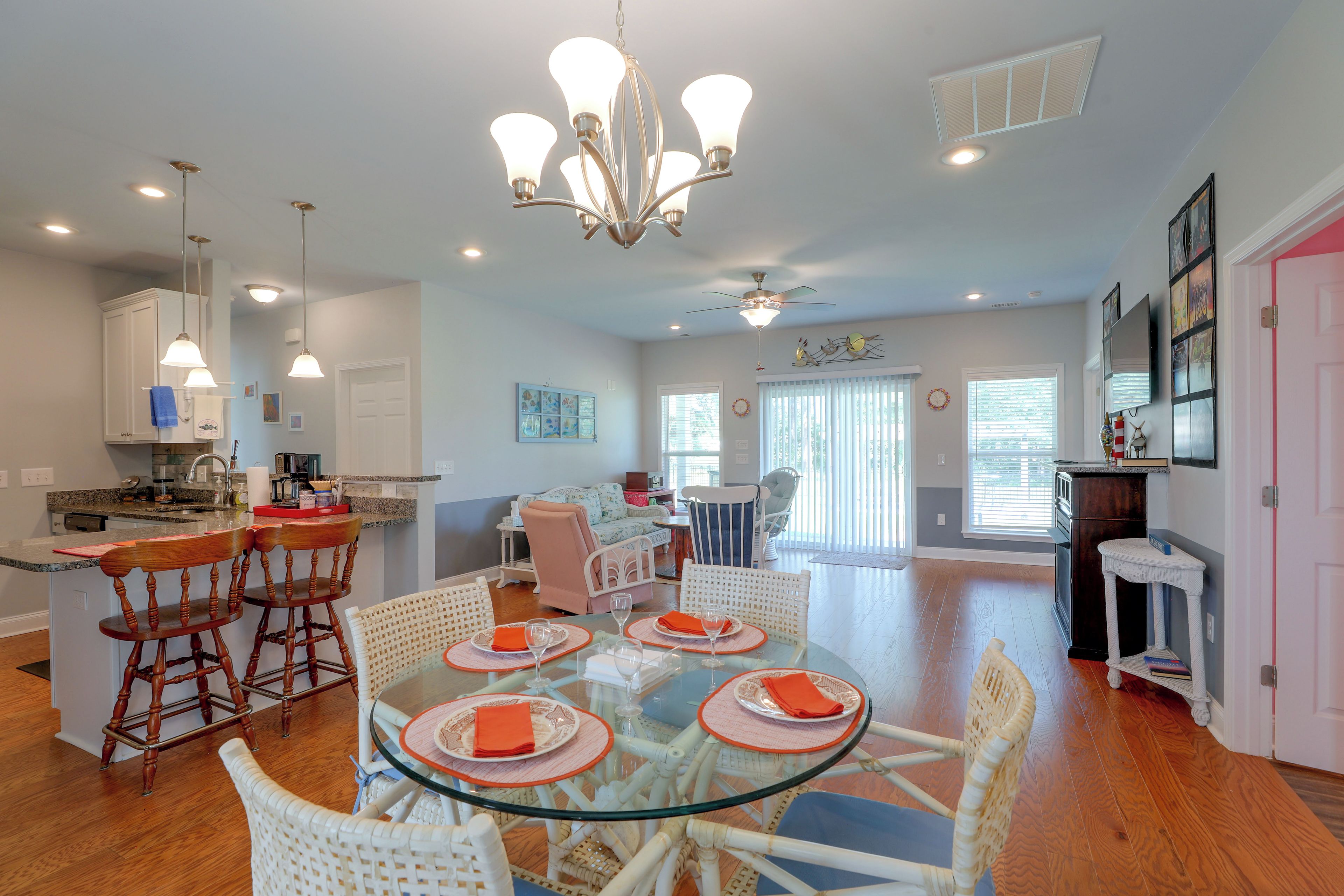 A spacious kitchen with a dining area, featuring a central island, bar stools, and a chandelier.