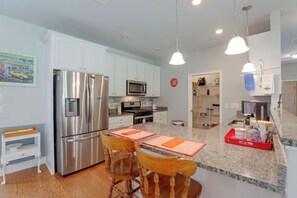 A modern kitchen with stainless steel appliances, a granite countertop, and a dining area with wooden chairs. - Lake Marion Retreat Dock Days & Backyard Nights (Summerton)