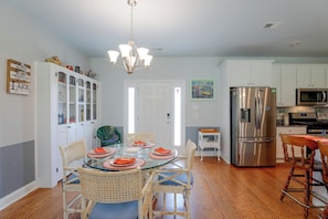 A modern kitchen with white cabinets, a stainless steel refrigerator, and a dining area with a glass table and wicker chairs. - Lake Marion Retreat Dock Days & Backyard Nights (Summerton)