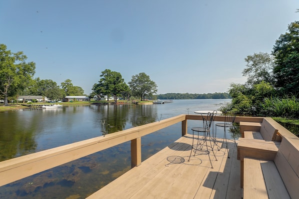 A wooden deck with a view of a lake, surrounded by trees and a dock with boats. - Lake Marion Retreat Dock Days & Backyard Nights (Summerton)