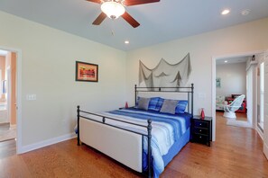 A bedroom with a bed, a ceiling fan, a nightstand, a framed picture, and a doorway leading to another room. - Lake Marion Retreat Dock Days & Backyard Nights (Summerton)