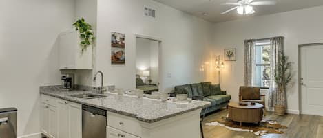 A modern kitchen with a central island, built-in dishwasher, and a ceiling fan.
