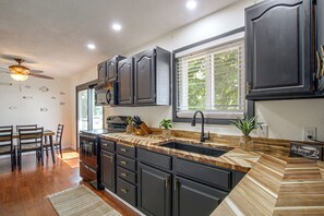 A modern kitchen with dark cabinetry, a wooden countertop, and a built-in oven.