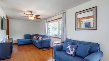 A living room with a sectional sofa, a small table, and a ceiling fan.