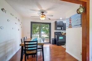 A dining area with a table and chairs, a ceiling fan, and a view through a glass door to an outdoor deck. - Spacious Home w/ Deck & Mississippi River Views (Grafton)