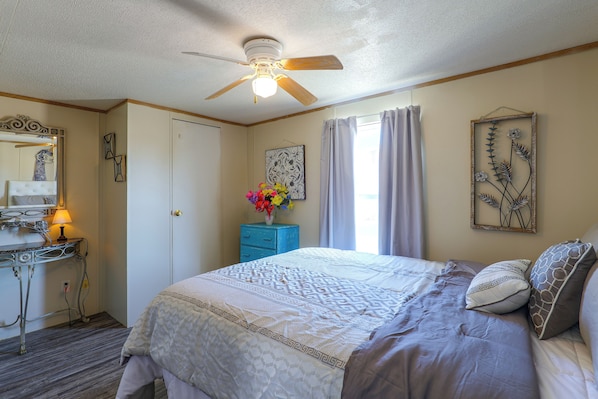 A bedroom with a bed, a dresser, a vanity, and a ceiling fan. - Fort Stockton Home, Your Big Bend Basecamp (Fort Stockton)