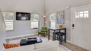 A living room with a sofa, a TV, a green chair, a small table, and a door.