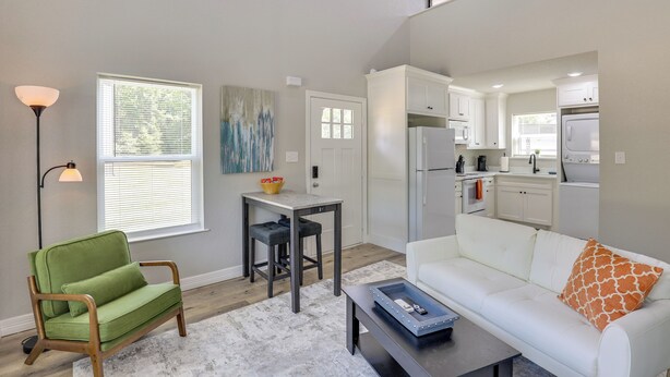 A modern living room with a green armchair, white sofa, and a coffee table.