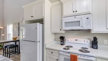 A kitchen with white cabinets, a refrigerator, a microwave, a stove, and a sink.