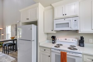 A kitchen with white cabinets, a refrigerator, a microwave, a stove, and a sink. - Stylish Tiny Home: 6 Mi to Gladewater Antiquing! (Gladewater)