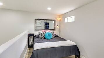 A bedroom with a bed, a bedside table, a mirror, and a nightstand.