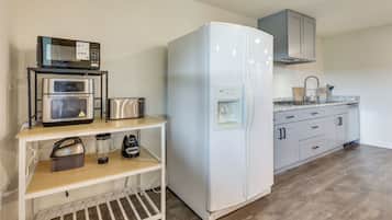 A compact kitchen with a white refrigerator, a microwave, and a toaster on a shelf.