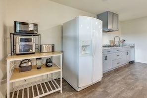 A compact kitchen with a white refrigerator, a microwave, and a toaster on a shelf.