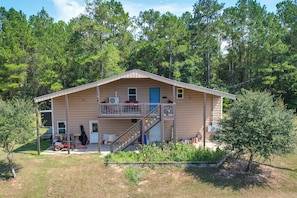 A two-story house with a balcony, a staircase, and a front yard with flowers.