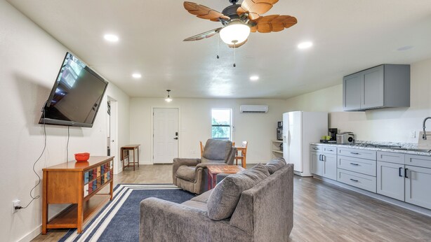 A modern living room with a sofa, a television mounted on the wall, and a ceiling fan. - Orchard, Pond On-site! Farm Stay Near Point A Lake (Red Level)