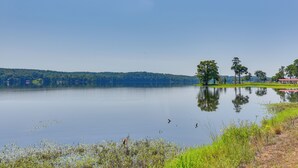 A calm lake with a clear reflection, surrounded by greenery and a few buildings in the distance. - Orchard, Pond On-site! Farm Stay Near Point A Lake (Red Level)