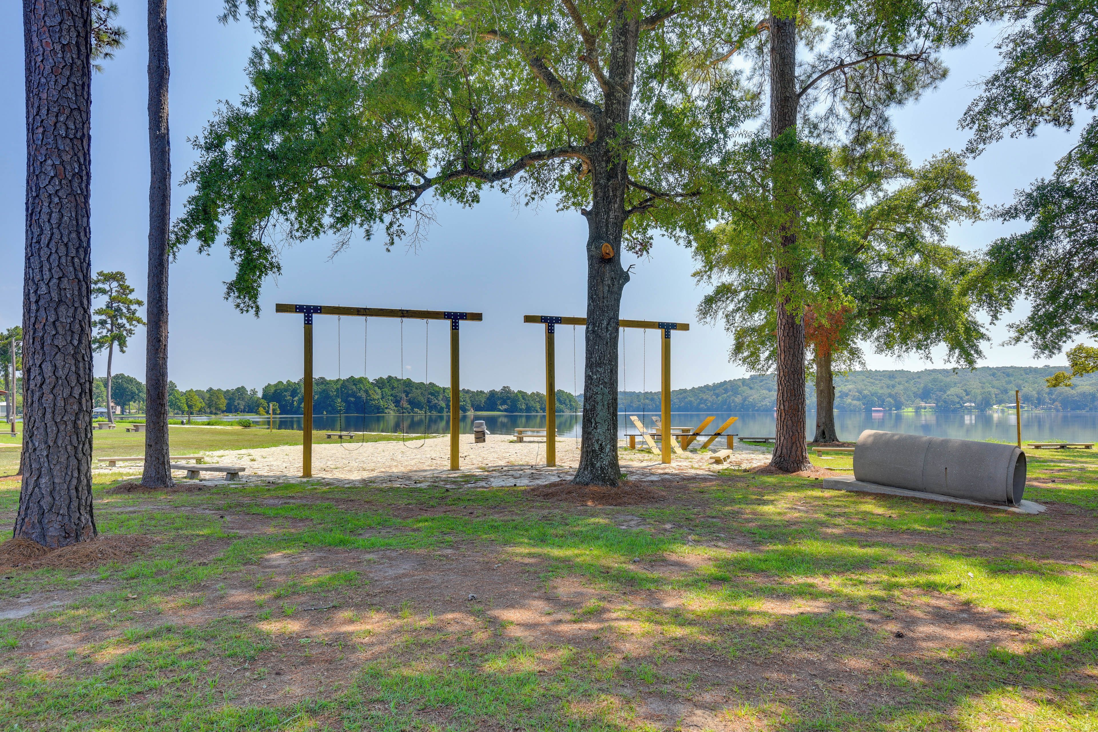 A park with swings, a picnic area, and a view of a lake.