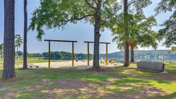 A park with swings, a picnic area, and a view of a lake.