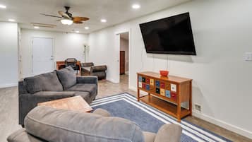 A living room with a sectional sofa, a television mounted on the wall, and a wooden cabinet with drawers.