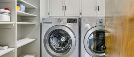 A laundry room with two front-loading washing machines and white cabinets above.