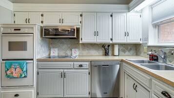 A kitchen with white cabinets, a stainless steel dishwasher, and a microwave.