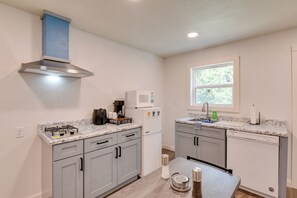 A modern kitchen with grey cabinets, a stainless steel range hood, a coffee maker, and a microwave.