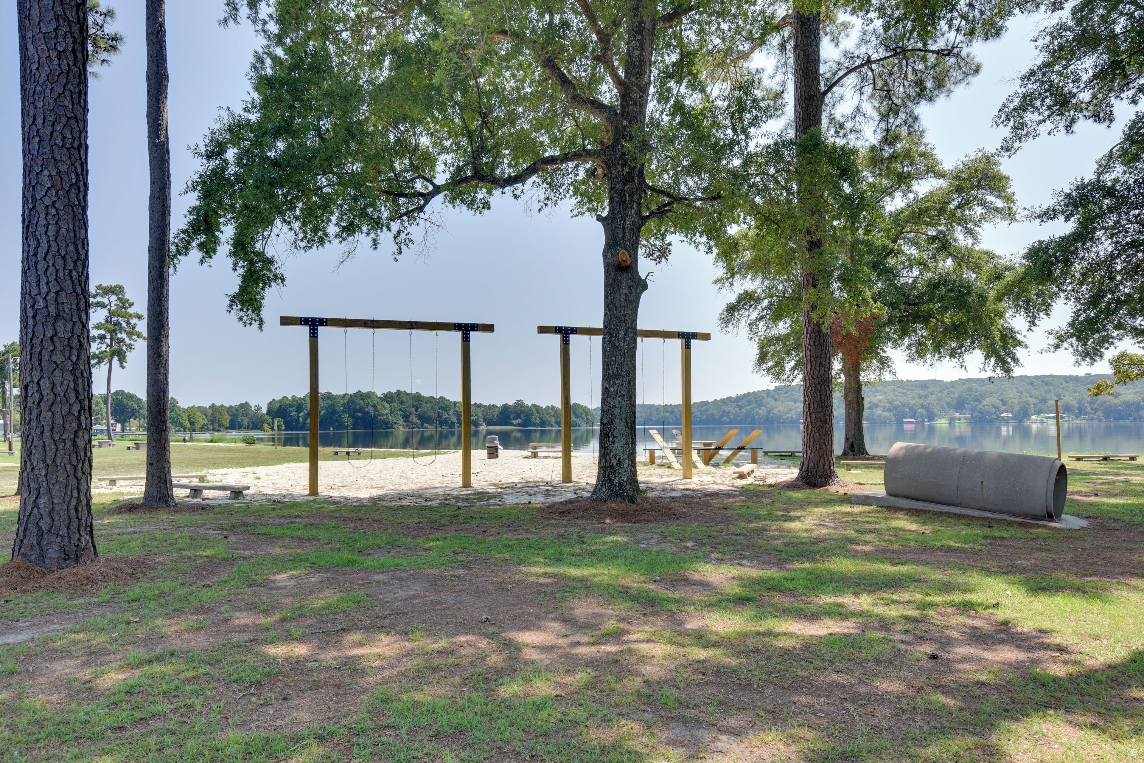 A park with swings, picnic tables, and a lake view.