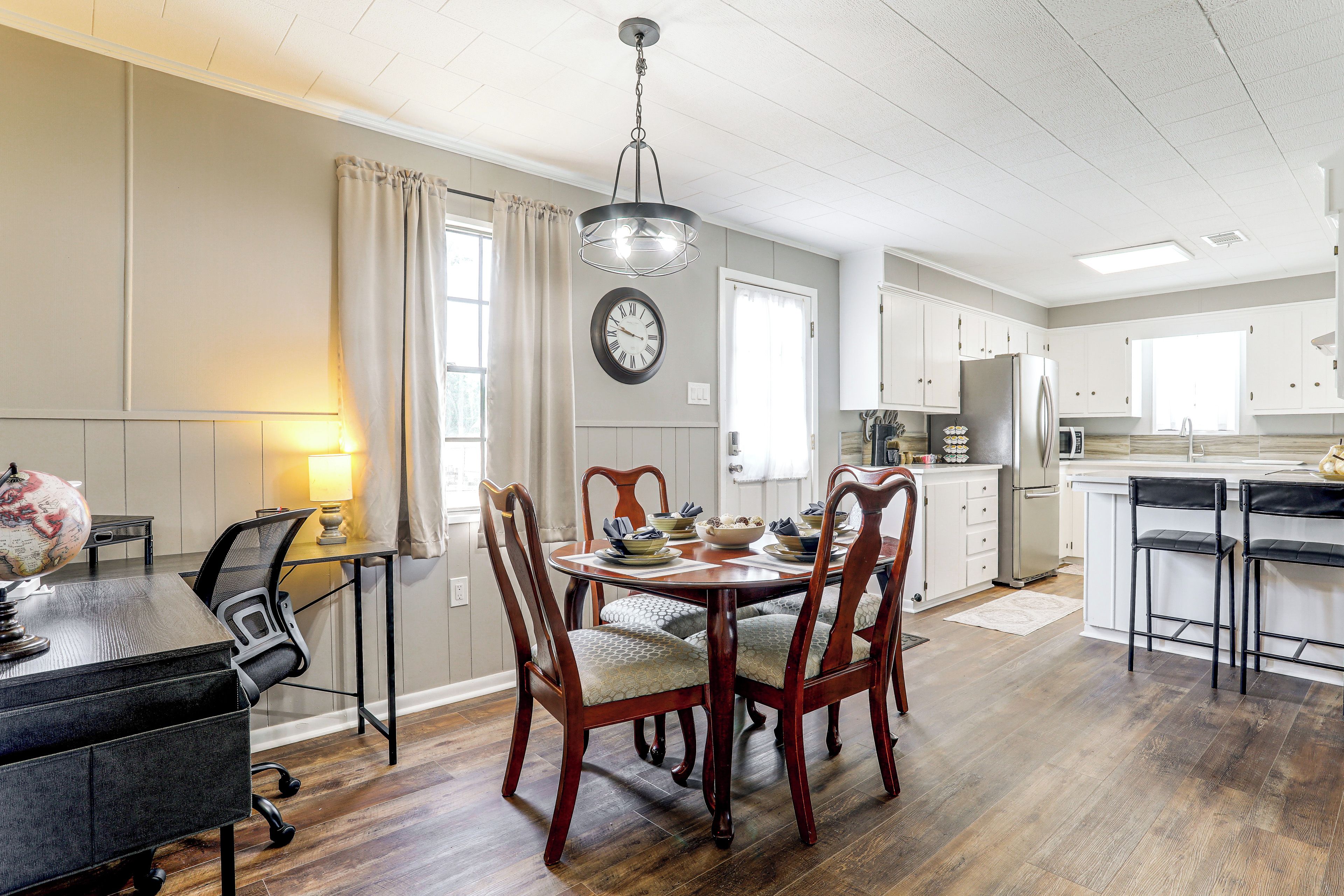 A dining area with a wooden table and chairs, a globe, and a lamp on a desk.